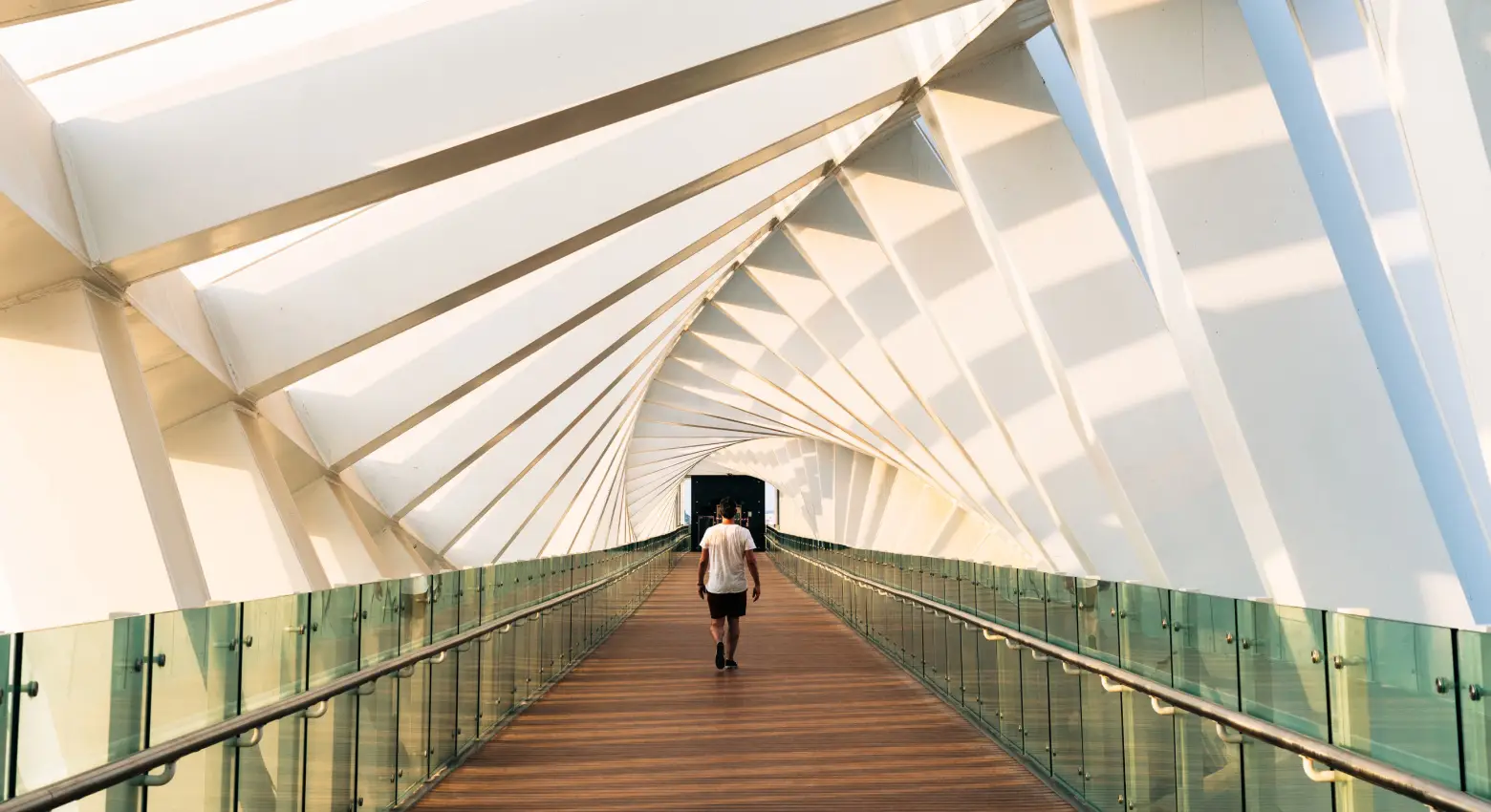Eine Person geht auf einer Brücke zwischen moderner Architektur 