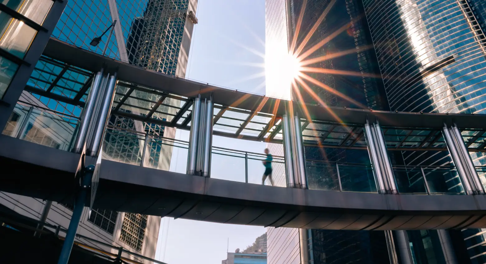 Eine Person geht auf einer Brücke zwischen moderner Architektur 