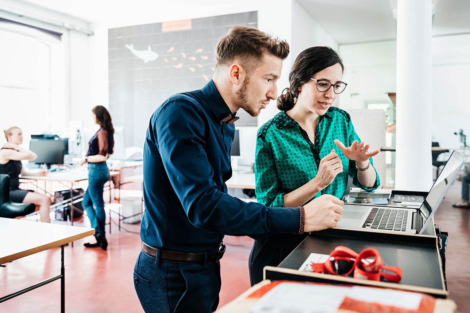 Eine Frau und ein Mann diskutieren über Datenschutz, während sie auf einen Laptop schauen.